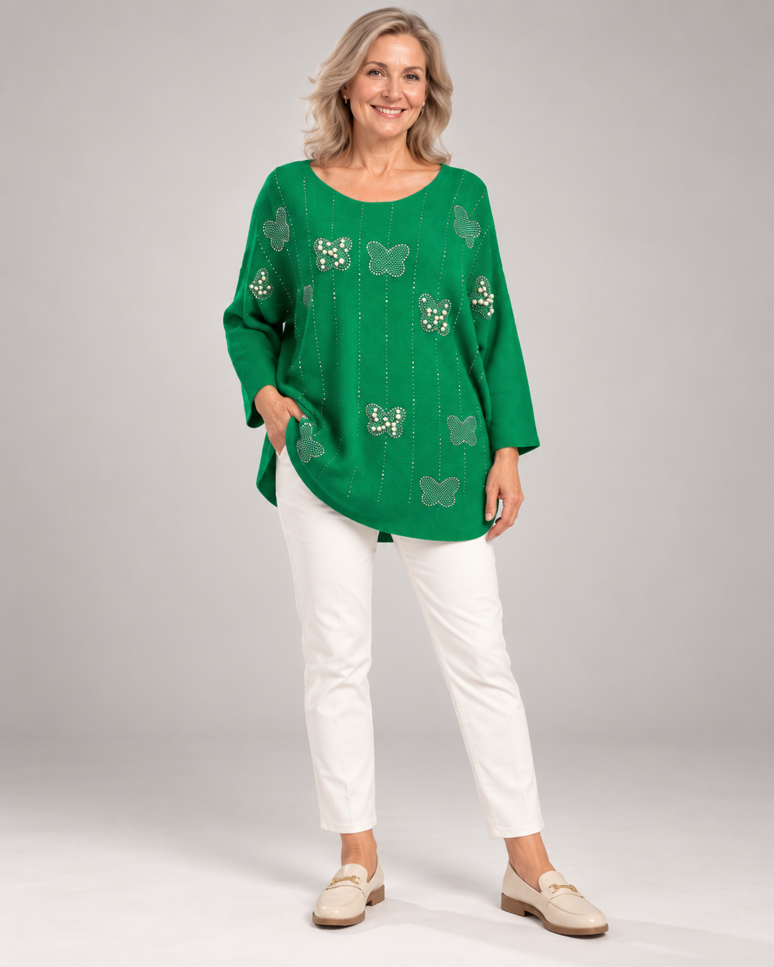 Grüner Strickpullover mit Schmetterlingen aus Strass und Perlen, Ganzkörper mit weißer Hose